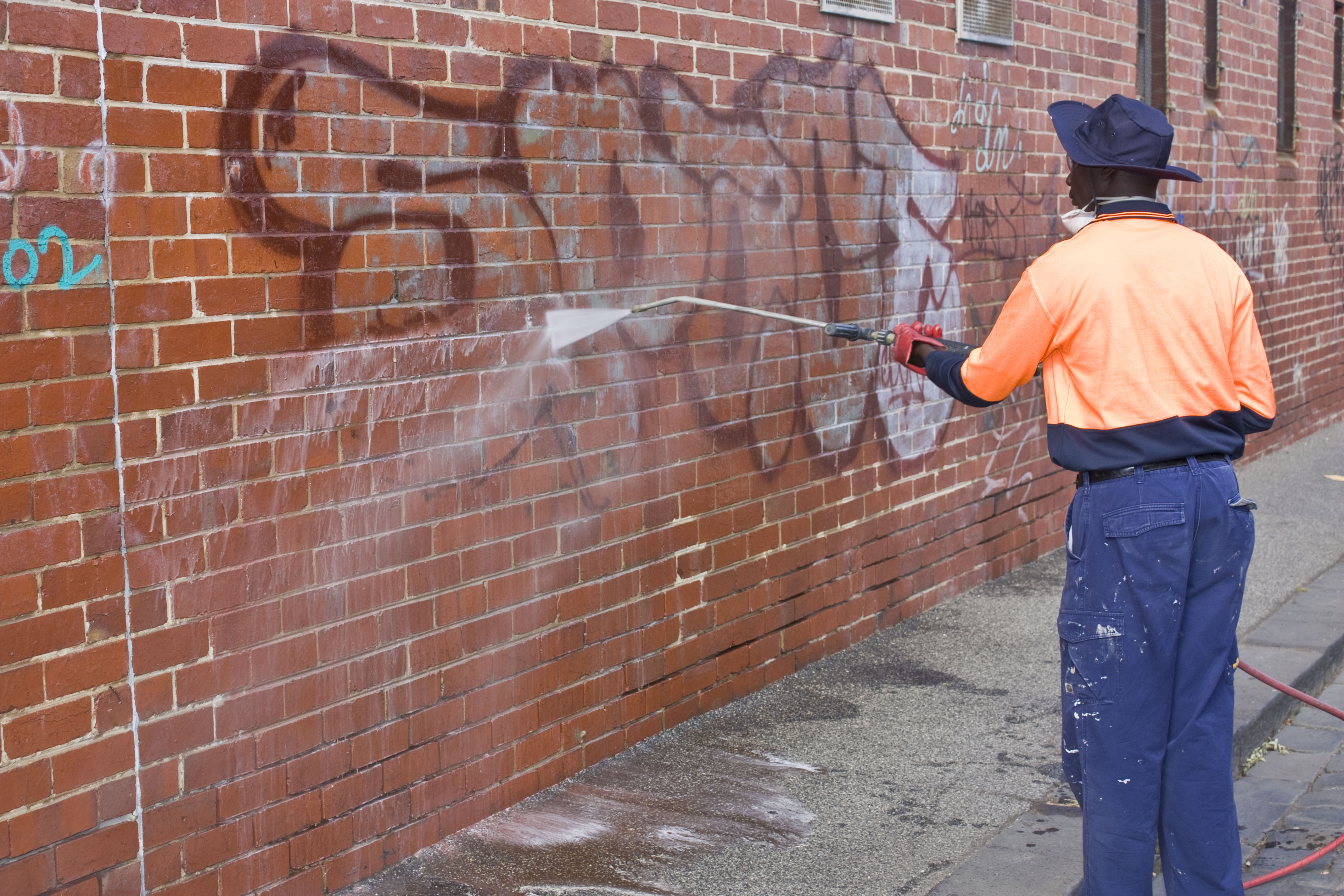 Person removing graffiti off a wall 