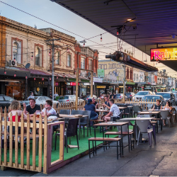 People sitting in outdoor dining  are on street, eating and drinking