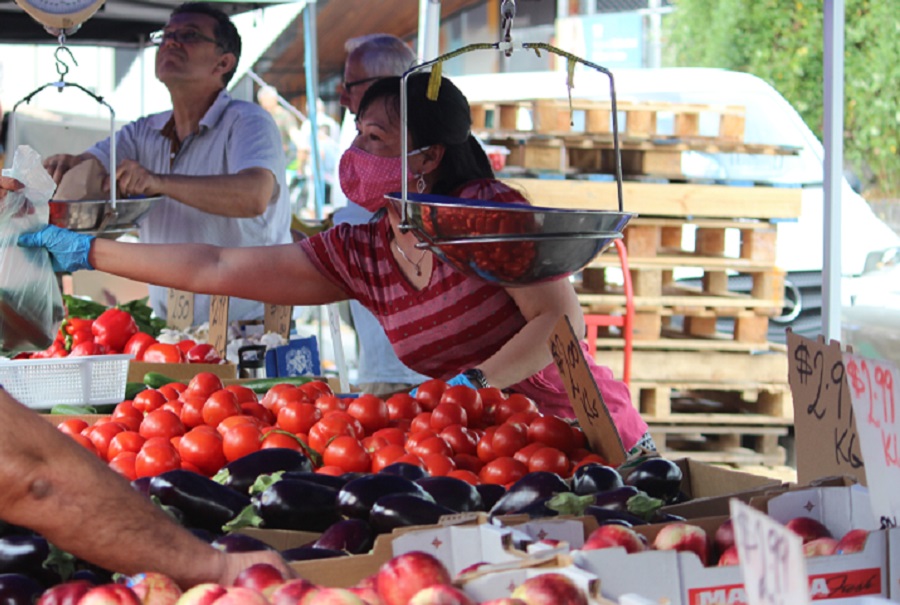 Picture of seller and customer buying fruit at a market.