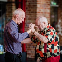 Two elderly men dancing together