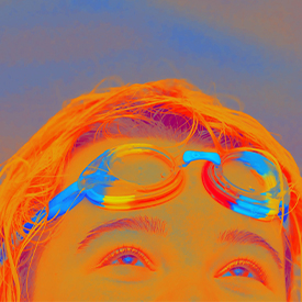 A orange filtered image of a persons face close up with goggles on their head and the word pride night in rainbow