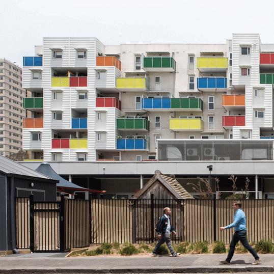 A white apartment block with rainbow coloured balconies