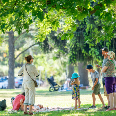 A group of adults and children stand in a sunny park