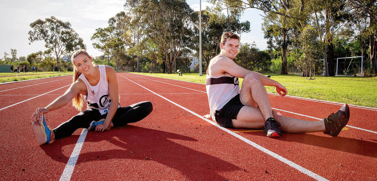A man and a woman stretching on an athletics track