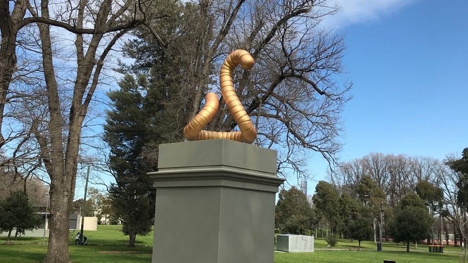 A golden worm sits above a plinth in the middle of Edinburgh Gardens