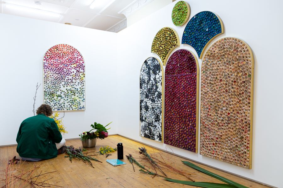 Person sitting on the floor installing a colourful artwork on the walls.