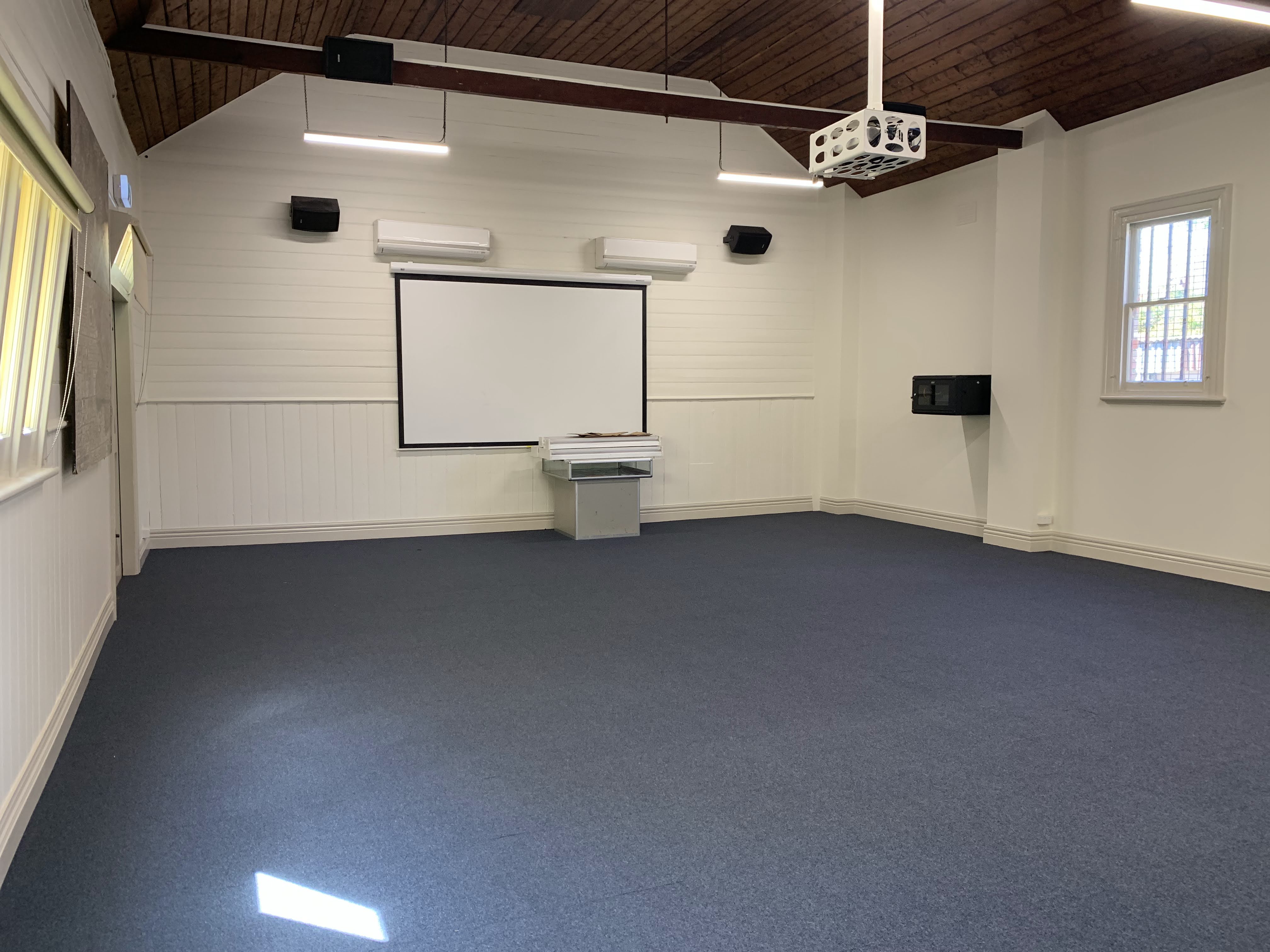 Image of a empty room with blue carpet and a dropdown screen