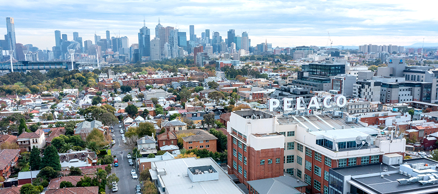 Drone aerial photo looking over Richmond suburb rooftops, the PELACO sign is in the foreground with the Melbourne city buildings just visible in the background