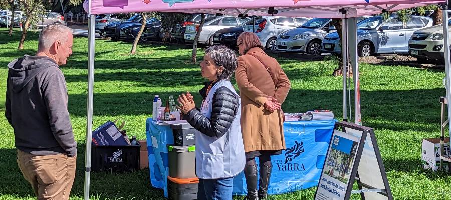 A Yarra staff member chats to a community member at a stall in a park