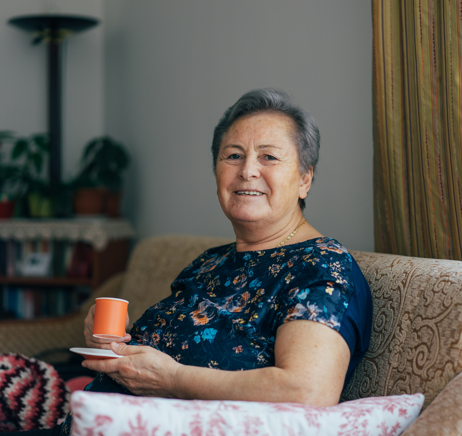 Older woman smiling while holding a hot beverage 