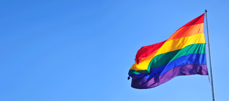 Rainbow flag flying outside on a blue sunny sky