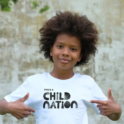 A child pointing to their tshirt which says child nation