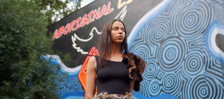 young woman in front of Aboriginal Lives Matter mural in Collingwood