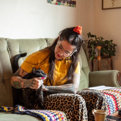 A person sitting on a couch and petting a cat