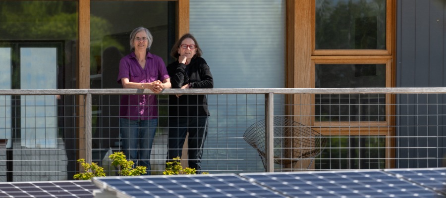 Two people standing on a balcony with solar panels in the foreground beneath them
