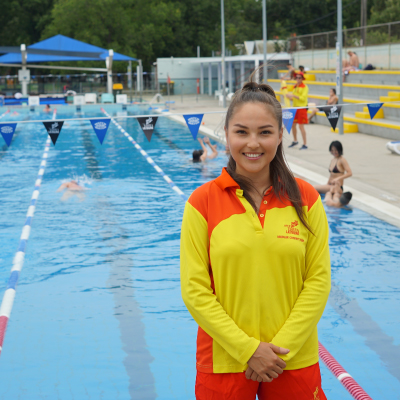 female lifeguard standing in front of an outdoor pool