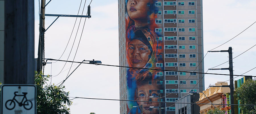Photo of a housing estate tower in Collingwood with a mural of faces painted on it