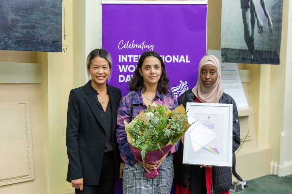 Cr Mi-Lin Chen Yi Mei with two women from The Drum Yarra holding a certificate and bunch of flowers
