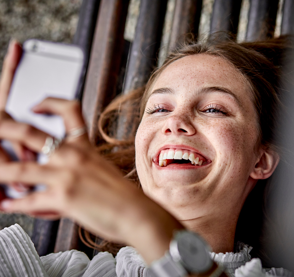 Woman laughing while looking at her mobile phone