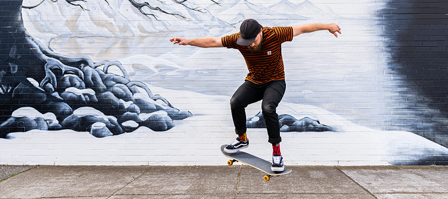 man on skateboard doing a trick in front of a blue and white snow themed mural