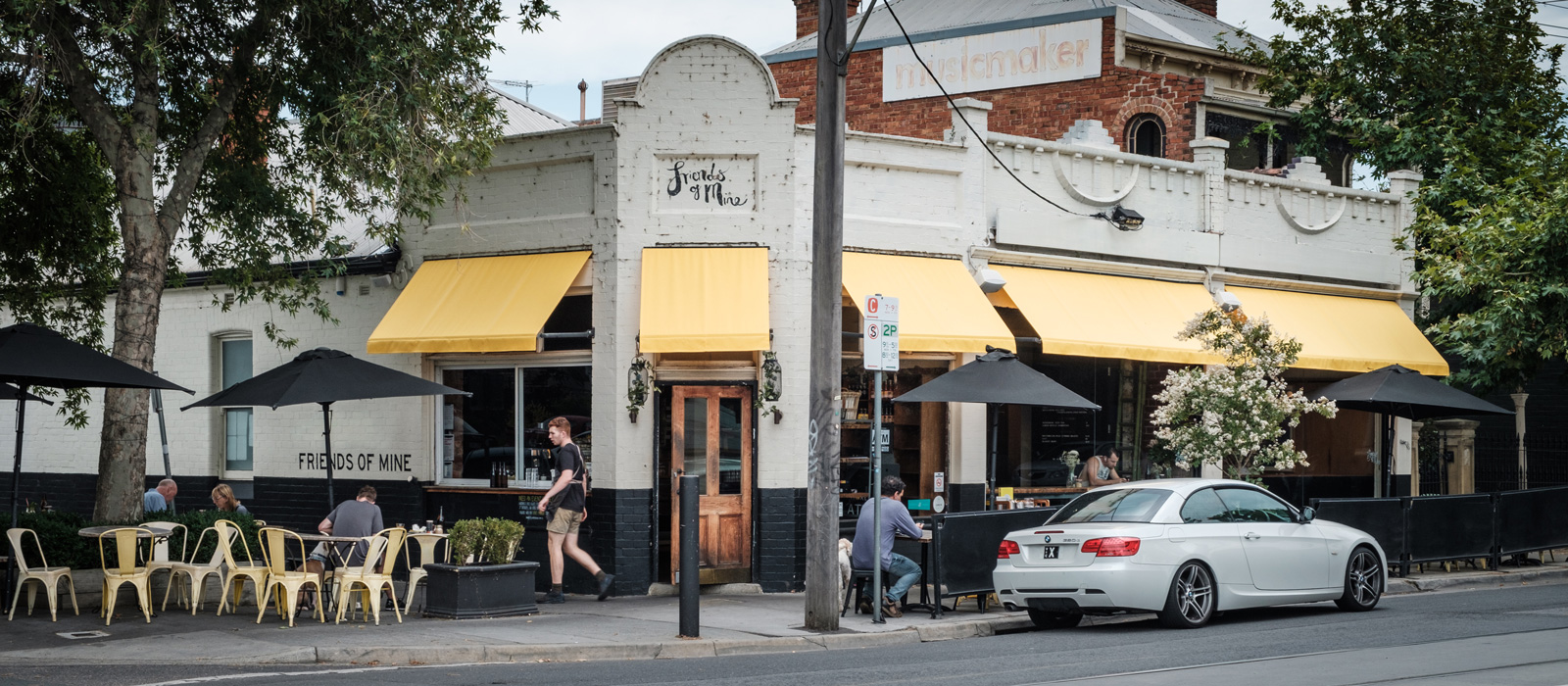 Cafe on Swan Street with outdoor tables and bright yellow awnings. 
