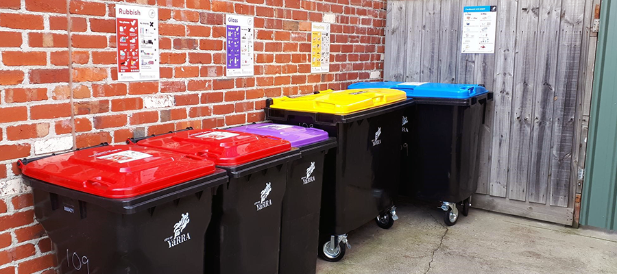 red, purple, yellow and blue lidded bins arranged with flyers for residents