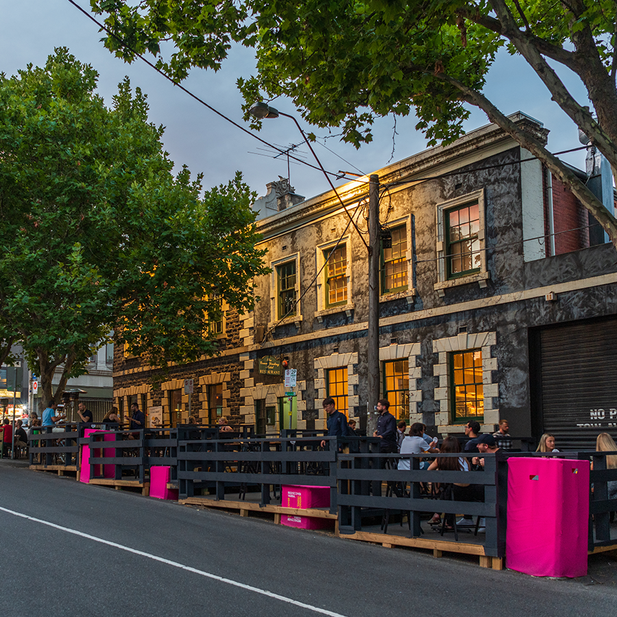 parklet at dusk with grey fencing and patrons seated at tables