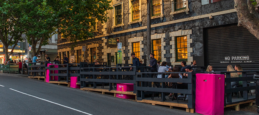 parklet at dusk with grey fencing and patrons seated at tables