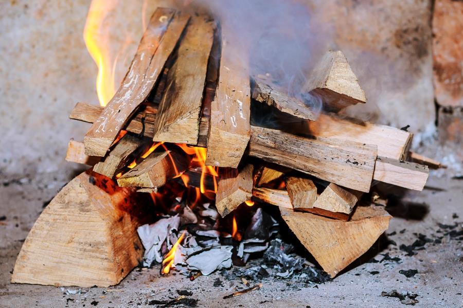 A close-up image of wood fire kindling burning and emitting smoke. 