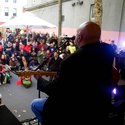 Archie Roach performing to a crowd with his guitar