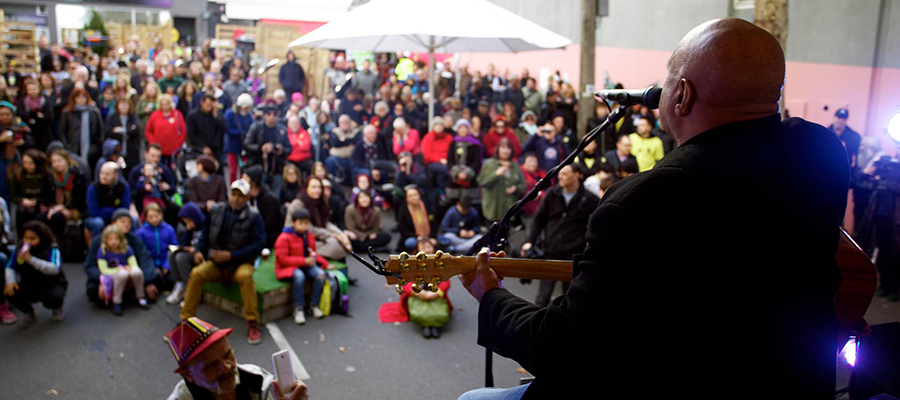 Archie Roach performing to a crowd with his guitar