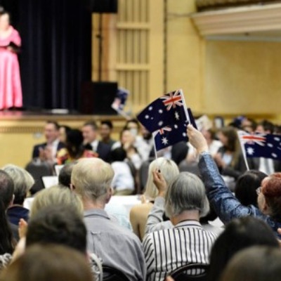 Audience waving Australian flags at a citizenship ceremony