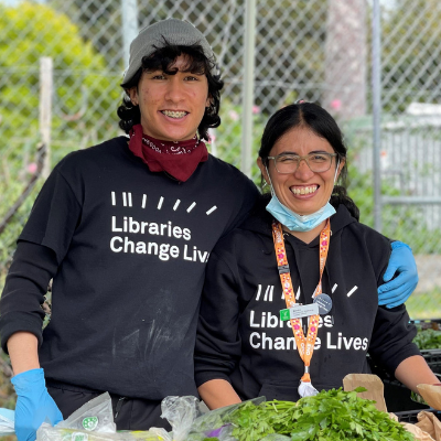 Two library staff members, wearing Libraries Change Lives t-shirts and smiling
