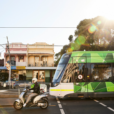 Scooter rider and tram drive down Nicholson Street