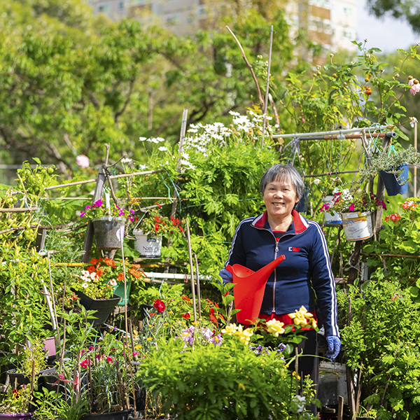 Woman with red watercan standing in community garden