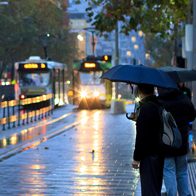 People waiting with umbrellas at a tram stop