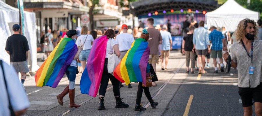 Three people walking down a street holding rainbow flags