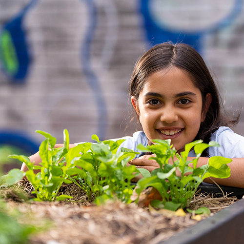 Smiling child in front of plants in urban garden