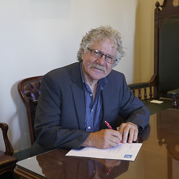 Cr Glynatsis signing a document at his desk