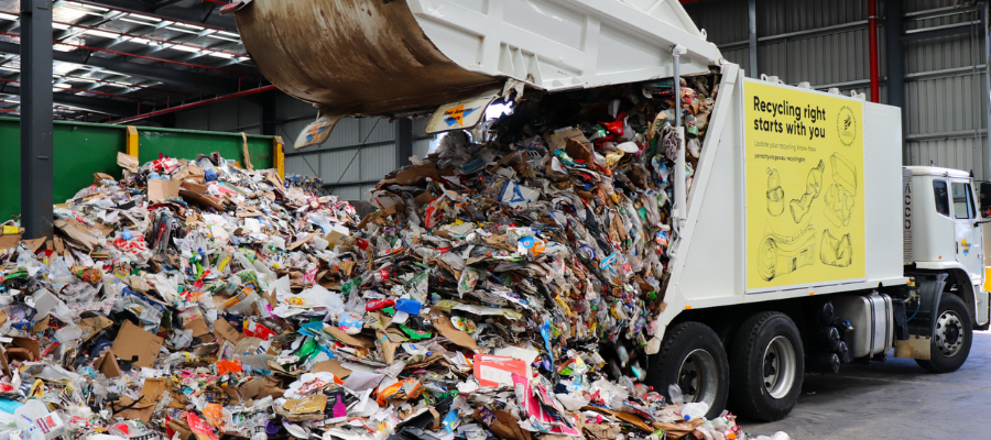 Recycling truck pouring out recycling contents onto warehouse floor