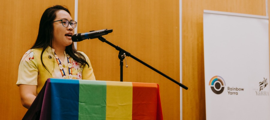 Mayor Claudia Nguyen speaking at Yarra's IDAHOBIT event with a rainbow flag draped over the lectern