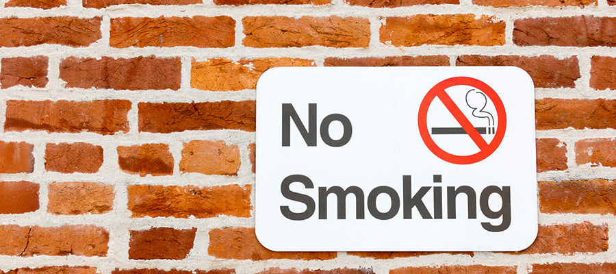 No Smoking sign hanging on a brick wall 