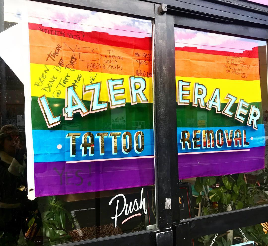 Rainbow flag in window of tattoo removal shop in Collingwood