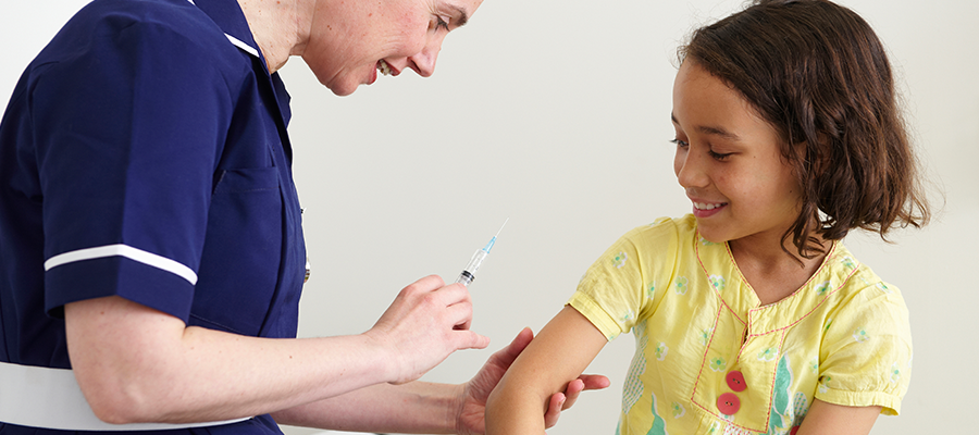 A young girl is receiving a vaccine from a nurse.