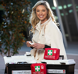 Blonde woman looking at the camera with first aid kits in front of her