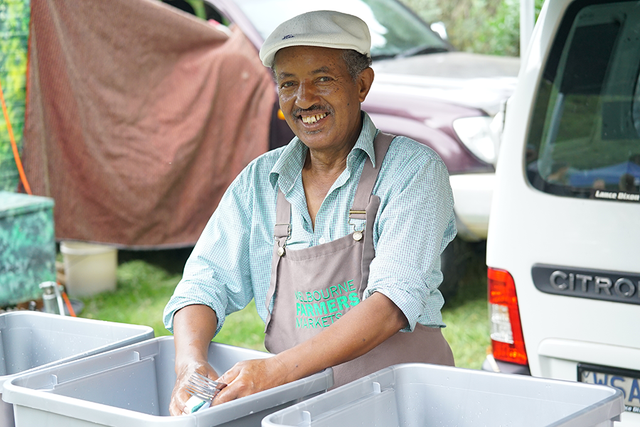 Ethiopian man washing dishes in bucket at farmers market