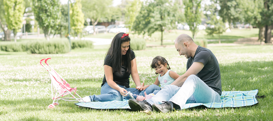 Family sitting on picnic rug on grass in Yarra park
