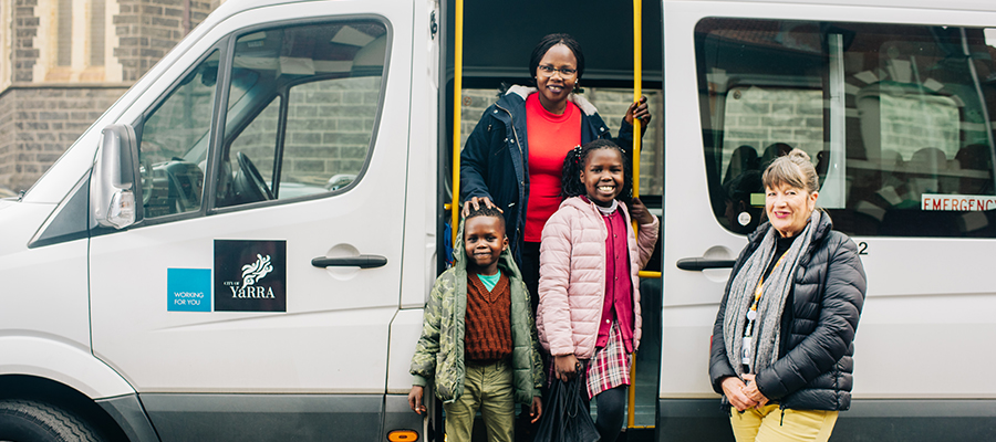 A family and the counil bus driver standing by the bus door smiling