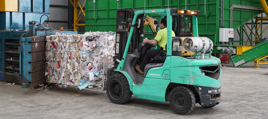 Man driving forklift with bale of paper