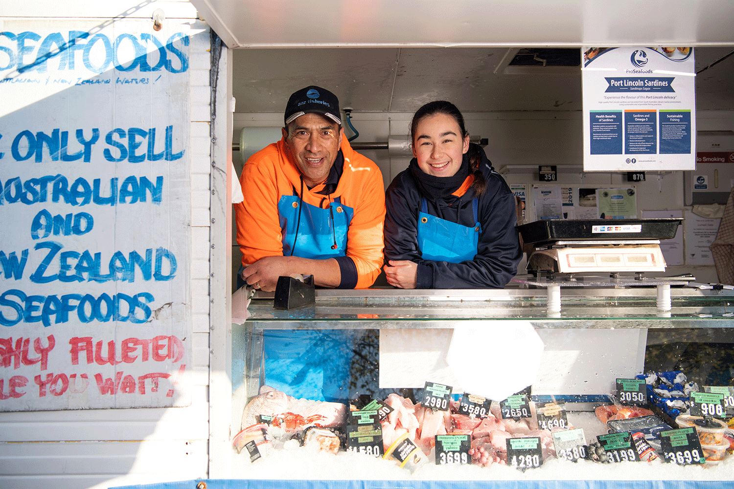 A man and a woman smiling in a mobile store with seafood for sale